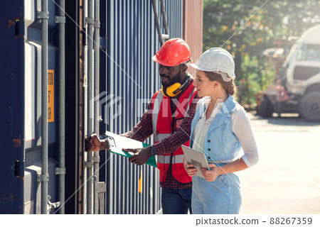 Businesswoman and engineer talking and checking loading Containers box from Cargo freight ship for import export. shipping in docks. Businesswoman and engineer talking and checking loading Containers box from Cargo freight ship for import export. shipping in docks. 88267359