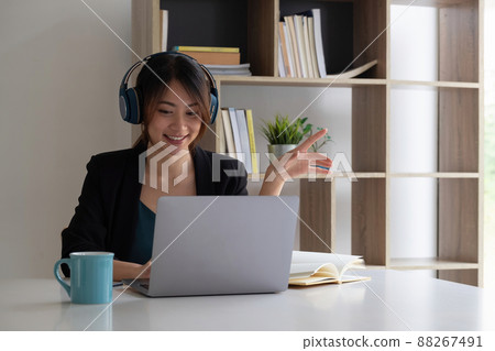 Happy asian woman wear headset laugh using laptop video stream conference call teach online, happy ethnic girl student gamer tutor have fun watch webinar web cam education entertainment concept 88267491