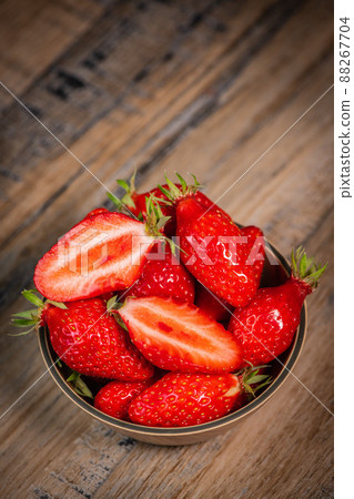 Fresh strawberries in a bowl on wooden table with low key scene 88267704