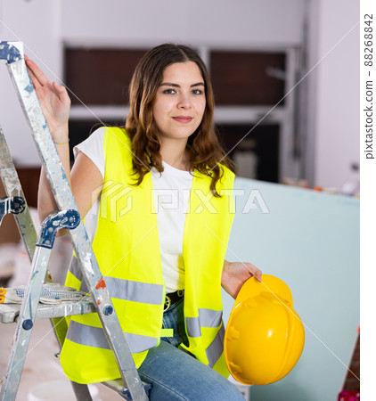 Enthusiastic female builder in yellow workwear inside house under construction Enthusiastic female builder in yellow workwear inside house under construction 88268842