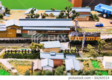 A diorama of a countryside with miniature cars, trains and people 88269314