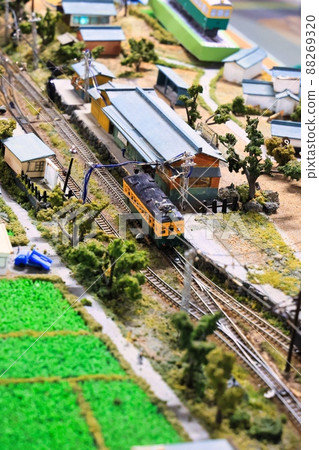 A diorama of a countryside with miniature cars, trains and people 88269320