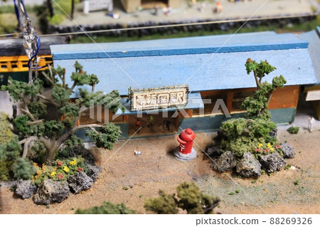 A diorama of a countryside with miniature cars, trains and people 88269326