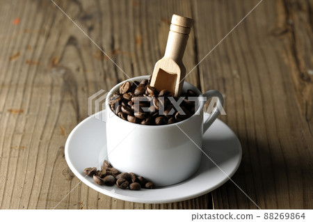 Coffee beans in a coffee cup and a measuring spoon that sticks into it 88269864
