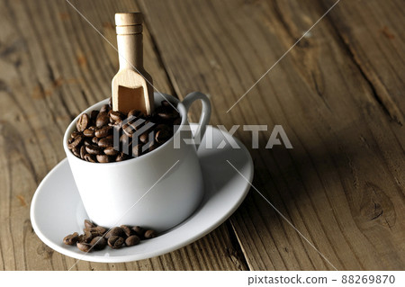Coffee beans in a coffee cup and a measuring spoon that sticks into it 88269870