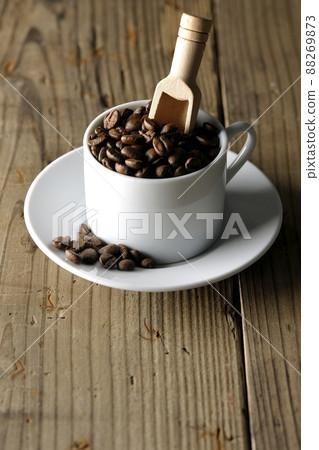 Coffee beans in a coffee cup and a measuring spoon that sticks into it 88269873