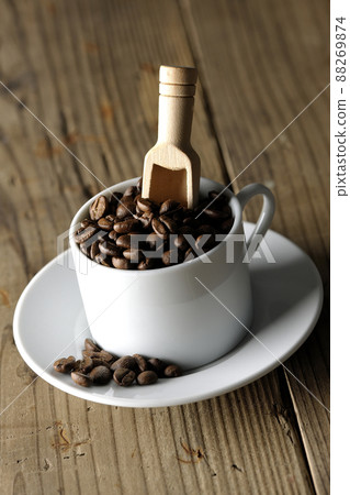 Coffee beans in a coffee cup and a measuring spoon that sticks into it 88269874