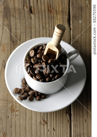 A bird's-eye view of coffee beans in a coffee cup and a measuring spoon stuck in it 88270396