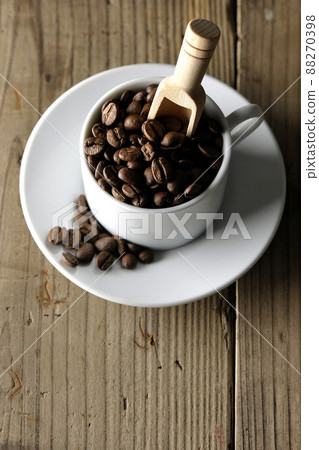 A bird's-eye view of coffee beans in a coffee cup and a measuring spoon stuck in it 88270398
