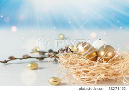 Golden colored Easter eggs in a nest on white wooden table over sky background. Happy Easter time. Golden colored Easter eggs in a nest on white wooden table over sky background. Happy Easter time. 88271462