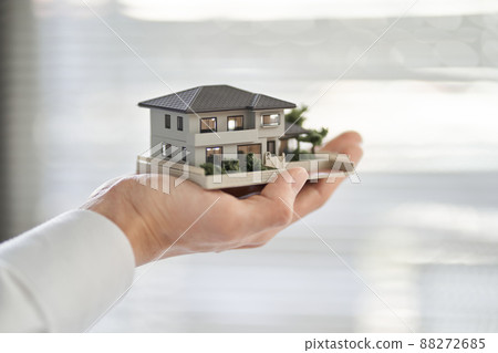 一個亞洲男人的手拿著一棟房子的建築模型 88272685