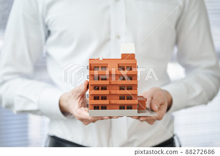 拿著公寓建築模型的一個亞裔人的手 88272686