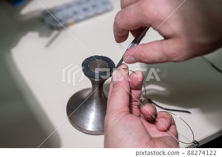 Optical technician fixing glasses. Close-up of male hands with screwdriver and goggles frame. 88274122