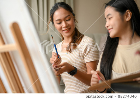 Two Asian sisters having a fun and happy time, painting and drawing on a canvas 88274340
