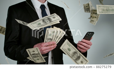 Close-up of businessman with flying dollars and smartphone 88275279