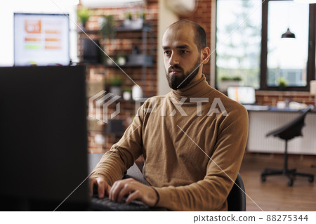 Office worker with financial knowledge seeking business recovery solution while using desktop PC. Marketing company employee sitting at desk, developing management plan while using work computer. Office worker with financial knowledge seeking business recovery solution while using desktop PC. Marketing company employee sitting at desk, developing management plan while using work computer. 88275344
