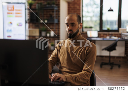 Development agency office worker analyzing project sales and fintech startup. Businessperson sitting at desk in marketing company office developing financial strategy and accounting management. Development agency office worker analyzing project sales and fintech startup. Businessperson sitting at desk in marketing company office developing financial strategy and accounting management. 88275352