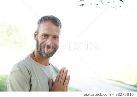 Namaste. Portrait of a handsome mature man standing with his hands in prayer position outdoors. Namaste. Portrait of a handsome mature man standing with his hands in prayer position outdoors. 88275816