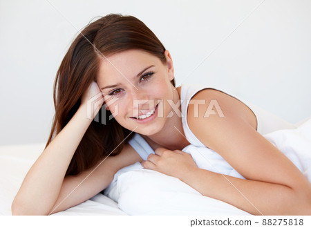 Enjoying sleeping in while on holiday. A gorgeous young woman smiling while lying in bed. 88275818