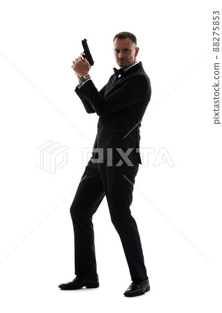 The agencys top spy. Studio shot of man in a tuxedo holding a gun isolated on white. The agencys top spy. Studio shot of man in a tuxedo holding a gun isolated on white. 88275853