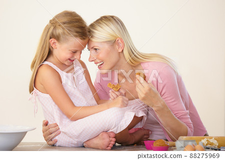 Cherishing every moment with her. A mother and daughter eating muffins after baking and bonding. 88275969