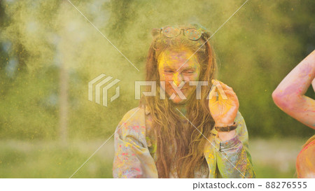 Friends sprinkle their cheerful girlfriend with multi-colored powder. Holi holiday. 88276555