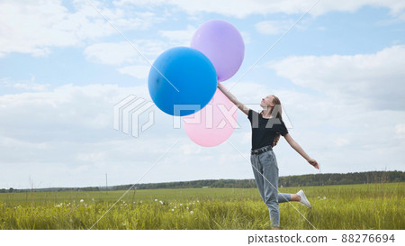 Happy girl with big multicolored balloons posing on the field. Happy girl with big multicolored balloons posing on the field. 88276694