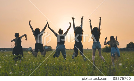 Girls friends are jumping against the background of an evening summer sunset. 88276700