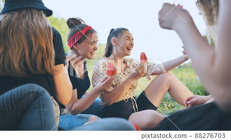 Friends have fun eating watermelon outside the city at a picnic. 88276703