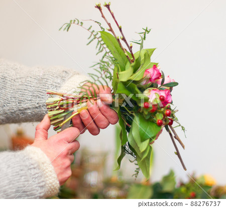 Every flower in its rightful place. Cropped view of a florists hands as she prepares a bouquet of flowers. 88276737