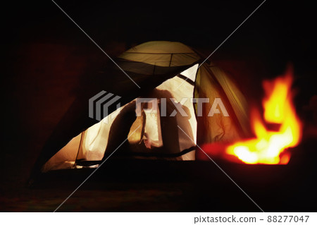 Tender moments while camping. Silhouette view of a young couple kissing in a tent. 88277047