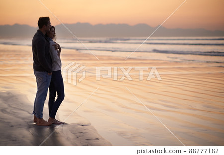 Theres nothing like young love. Silhouette of a young couple enjoying a romantic walk on the beach. 88277182