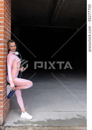 Sporty sexy young woman wearing pink sportswear and looking at the camera is using smartphone and Sporty sexy young woman wearing pink sportswear and looking at the camera is using smartphone and 88277700