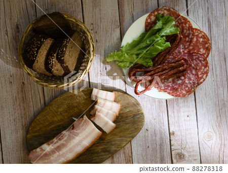 Bacon, sausage, salad and bread in a wicker basket on a wooden table Bacon, sausage, salad and bread in a wicker basket on a wooden table 88278318