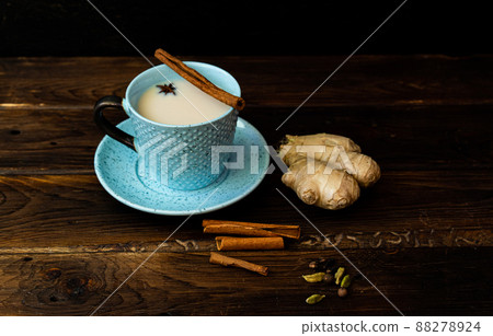 Indian tea masala chai. Seasoned chai masala tea with milk and spices on a dark wooden background. 88278924