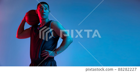 Portrait of young Korean man with basketball ball looking away isolated on blue studio background in neon light. Youth, hobby, sport concepts. 88282227