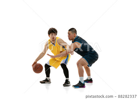 Dynamic portrait of two young basketball players playing basketball isolated on white studio background. Motion, activity, sport concepts. 88282337
