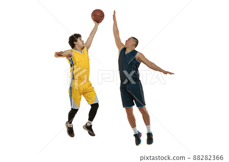 Full-length portrait of two young basketball players jumping with ball isolated on white studio background. Motion, activity, sport concepts. 88282366