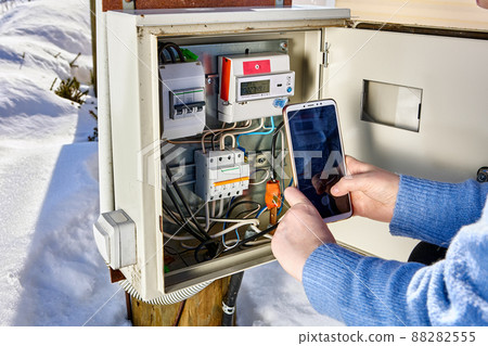 Taking readings from external electric meter and making picture by phone outdoors. 88282555
