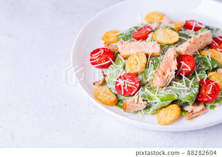 Caesar salad with red fish (salmon, trout), cherry tomatoes, croutons, parmesan cheese and romaine. Traditional American dish. Copy space. Close-up, selective focus. Caesar salad with red fish (salmon, trout), cherry tomatoes, croutons, parmesan cheese and romaine. Traditional American dish. Copy space. Close-up, selective focus. 88282604