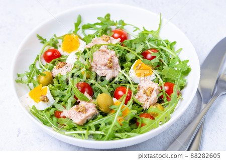 Salad with tuna, arugula, tomatoes, olives and eggs in a white plate. A traditional dish. Close-up. Salad with tuna, arugula, tomatoes, olives and eggs in a white plate. A traditional dish. Close-up. 88282605