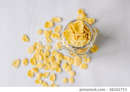 Corn flakes in a glass jar on white wooden surface. Top view. Place for your text Corn flakes in a glass jar on white wooden surface. Top view. Place for your text 88282753