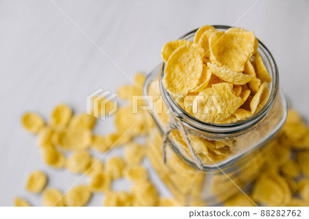 Corn flakes in a glass jar on white wooden surface. Top view. Place for your text Corn flakes in a glass jar on white wooden surface. Top view. Place for your text 88282762