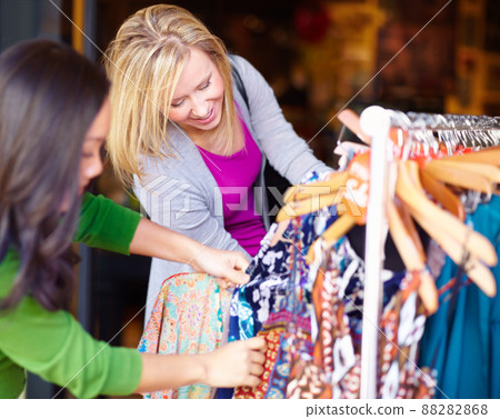 Raiding the sale rack. Two young woman looking through the sale items in a store together. Raiding the sale rack. Two young woman looking through the sale items in a store together. 88282868