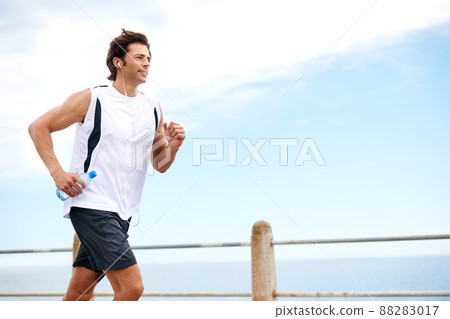 Building up his stamina. Cropped shot of a handsome young man running along the promenade. Building up his stamina. Cropped shot of a handsome young man running along the promenade. 88283017