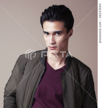 young pretty asian man posing in fashion style on light brown background, lifestyle people concept young pretty asian man posing in fashion style on light brown background, lifestyle people concept 88283684