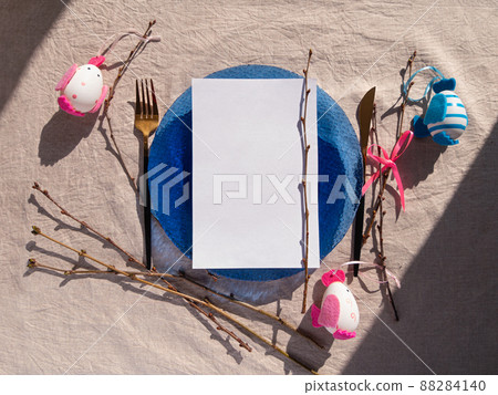 Easter table setting empty blue glass plate cutlery tree branches linen cloth flat lay harsh shadow Festive dish place 88284140