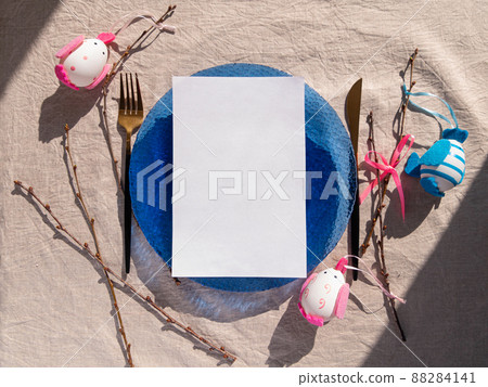 Easter table setting empty blue glass plate cutlery tree branches linen cloth flat lay harsh shadow Festive dish place 88284141
