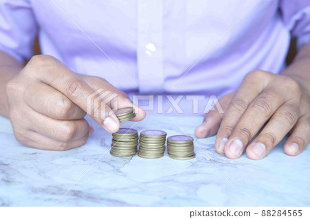 man's Hand putting stack of coins 88284565