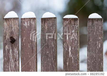 Fragment of an old wooden fence with snow, close up 88285192
